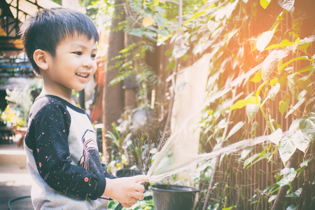asian boy is watering his home gardenの写真素材