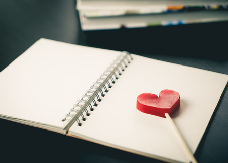 Heart stick on blank notebook on working deskの写真素材