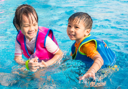 Asian siblings are having fun in the poolの写真素材
