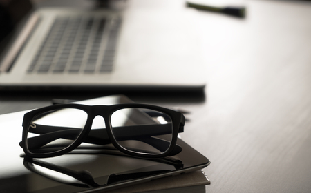 Glasses on office table with computer notebookの写真素材