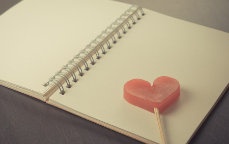 Heart stick on blank notebook diary on black tableの写真素材