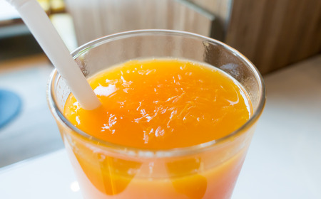 A glass of orange fresh juice on cafe tableの写真素材