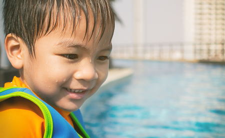 Wet Asian boy is sitting on poolsideの写真素材