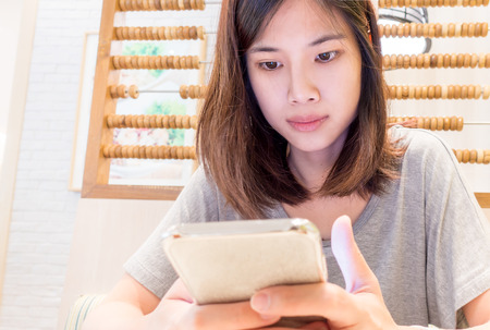 Asian girl is texting someone on her mobile phoneの写真素材