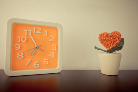 Orange clock with heart flower pot in vintage toneの写真素材
