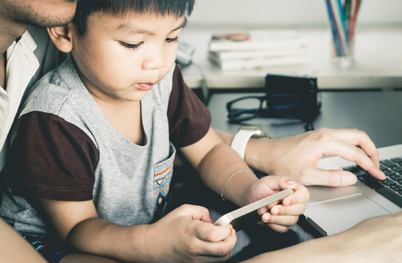 Asian boy is using Phone with Blank screen for mock up under father supervisionの写真素材