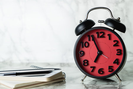 Red Alarm Clock in the morning with writing notebook