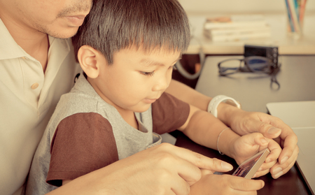 Father is teaching his son to use smartphone techonology wiselyの写真素材