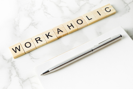 Workaholic text on marble office table with copy space on notebookの写真素材