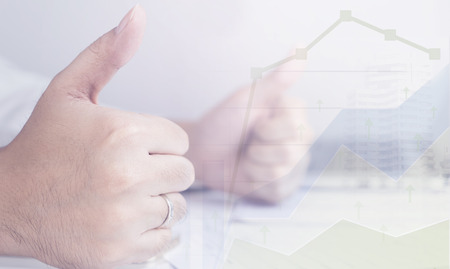 Business man is optimistic with his income graph with two thumbs upの写真素材