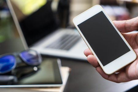 Business man is holding a blank hpone screen in office