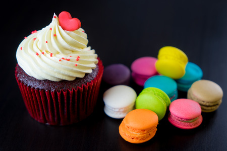 Heart topped cupcake with colorful macaronsの写真素材