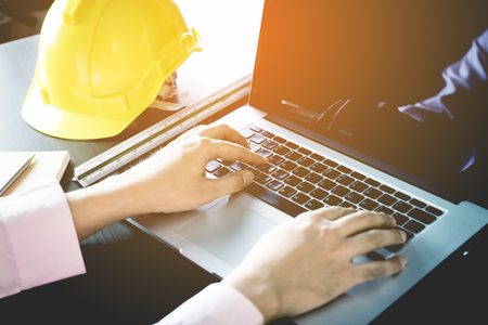 Engineer is working on computer with computer and safety helmet in officeの写真素材