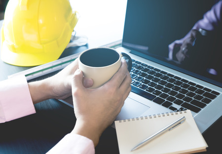 Engineer is having coffee working in morning in officeの写真素材