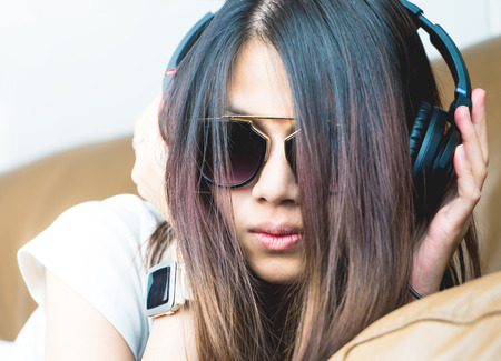 Asian fashion girl is listening to music on headphoneの写真素材
