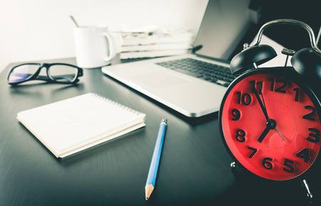 Red alarm clock on student working desk counting to deadlineの写真素材