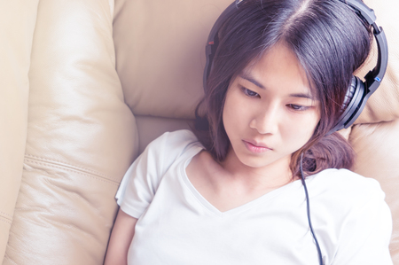 Cute Asian women is listen to music on the sofaの写真素材