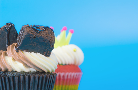 2 cupcakes chocolate and rainbow cupcake on blue background copy spaceの写真素材