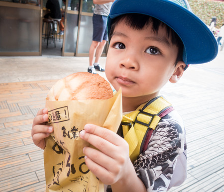 Tokyo, Japan - May 1, 2017: Asian Kid is eating Asakusa's Famous Melonpan bread.のeditorial素材