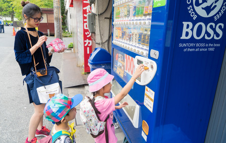 Tokyo; Japan - May 1; 2017: Family are buying soft drink cans from coin vendors.のeditorial素材