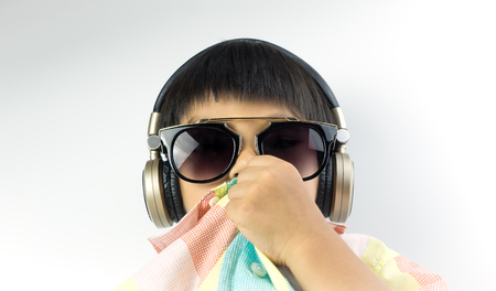 Asian boy with sunglasses is listening to music on headphoneの写真素材