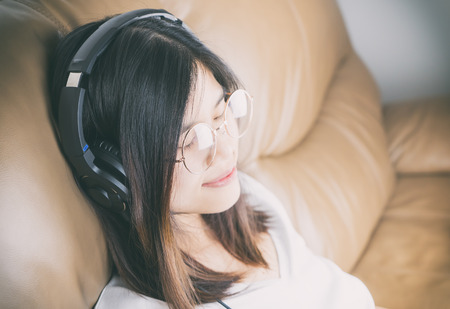 Girl with glasses is enjoying music on headphoneの写真素材