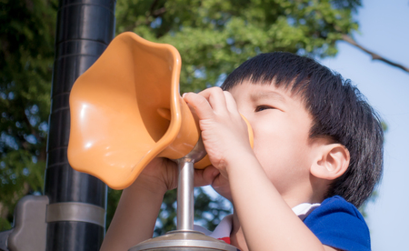 Boy is screaming into playground toy megaphoneの写真素材