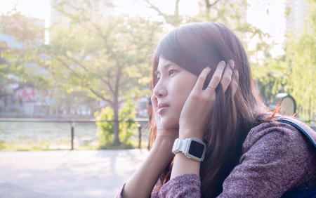 Pretty Asian girl is sitting in a bright sunlightの写真素材
