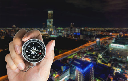 Hand holding a Compass in for direction complication urban city concept