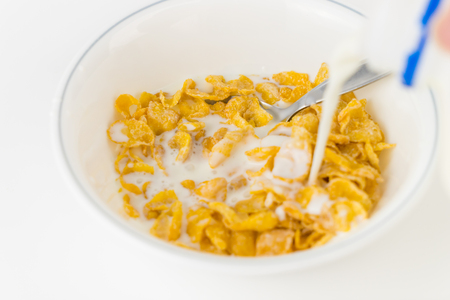 Pouring milk onto a bowl of sweetened cerealの写真素材