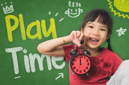 Little girl is holding a clock ready for playtimeの写真素材