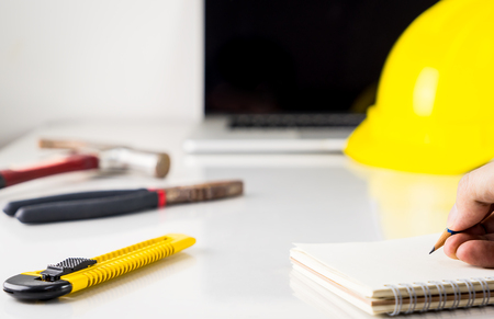 Engineer is taking note on a desk full of construction equipmentの写真素材