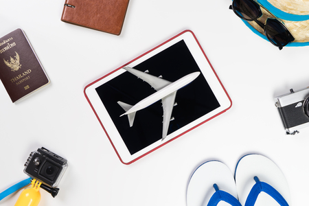 Air plane on tablet surrounded by travel accessoriesの写真素材