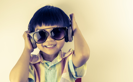 Asian boy is having fun listening to headphone in golden toneの写真素材