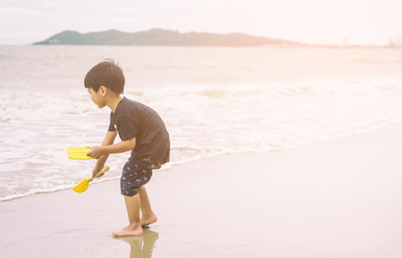 Boy is playing with sand and wave on the beachの写真素材