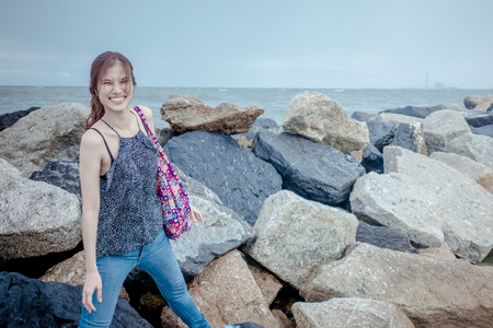 Asian lady standing on rock sea shoreの写真素材