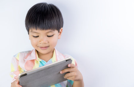 Asian kid is playing education game on tablet on white background