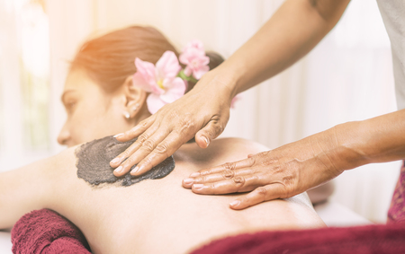 Spa Therapist is rubbing Charcoal scrub on a women backの写真素材