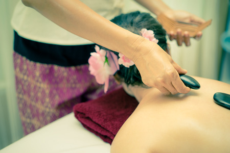 Women is getting Hot stone placed on her back by therapistの写真素材