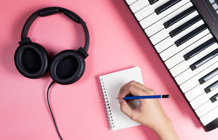 Musician is writing on notebook with studio  pink copy spaceの写真素材