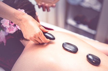 Spa Therapist is placing hot stone on to a women back