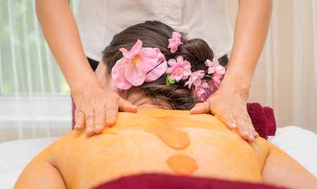 Therapist is rubbing orange salt on to a women backの写真素材