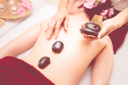 Laying down Spa hot stone on to a women backの写真素材