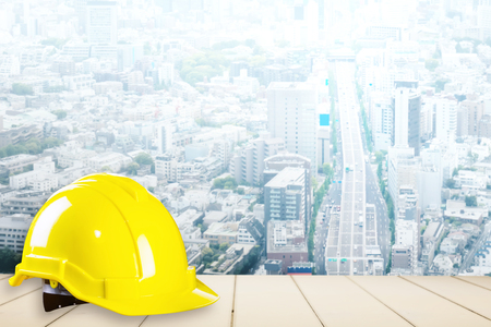 Yellow construction safety helmet with city backgroundの写真素材