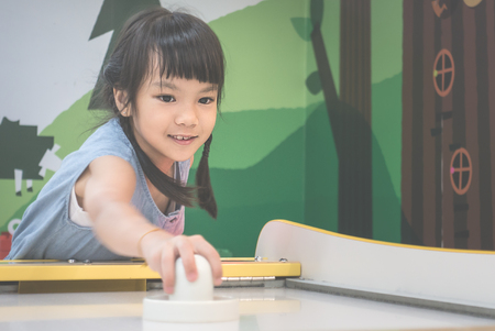 Little girl is playing a game of Air Hockeyの写真素材