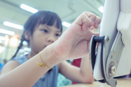 Kid using tablet on classroom table, focusing on the hand and tabletの写真素材