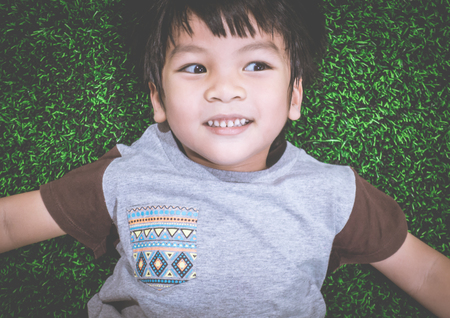 Happy Boy lying down on grass field top viewの写真素材