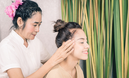Woman is getting head massaged in Thai massage spaの写真素材