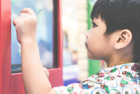 Boy is using his hand to play on touch screen display technologyの写真素材
