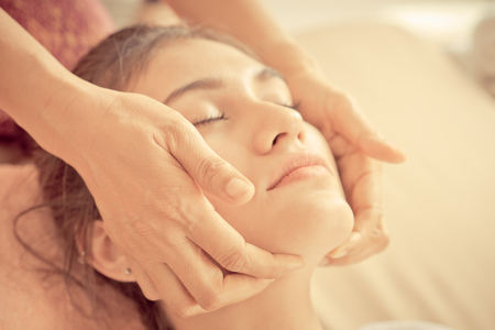 Therapist hand is massaging on a woman face in spaの写真素材